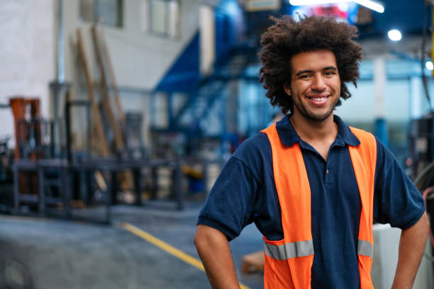 Portrait of a happy young man working in warehouse. Male warehouse worker in uniform looking at camera and smiling.